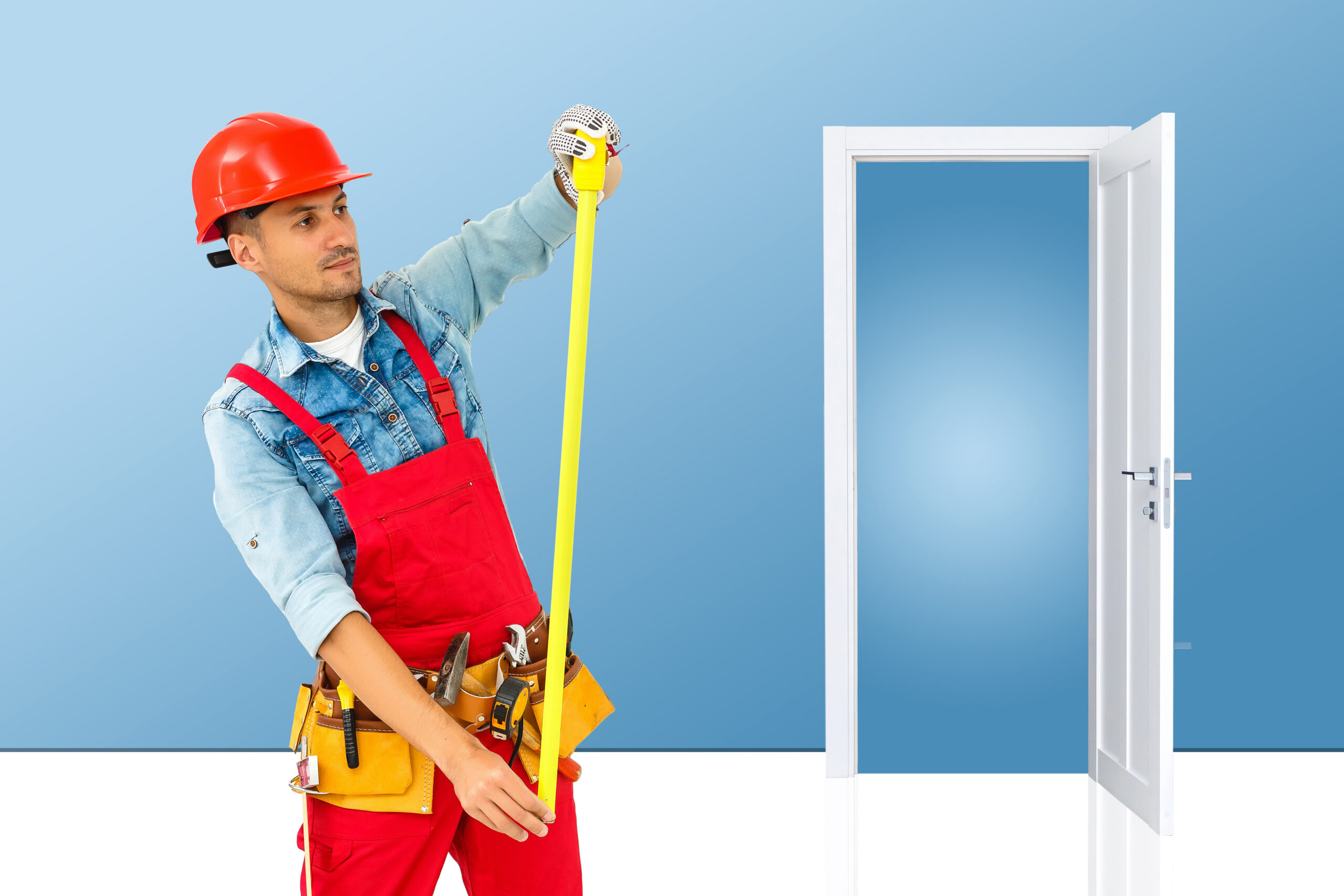 Young handyman installing a white door with an electric hand drill in a room