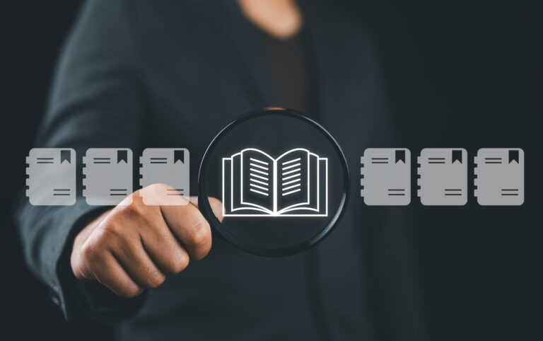 E library concept. Businessman use magnifying glass focus to virtual Ebook icons for electronic books online, knowledge base on internet, digital library or e library.